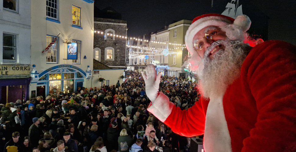 Crowds of people with a Santa waving in the foreground 